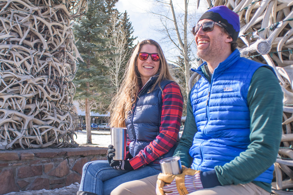 Couple sitting beside elk antler arch in Town Square Jackson WY