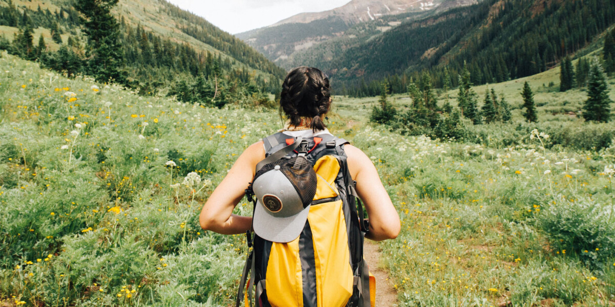 View during the summer of the back of a hiker looking into a mountain valley surrounded by mountains
