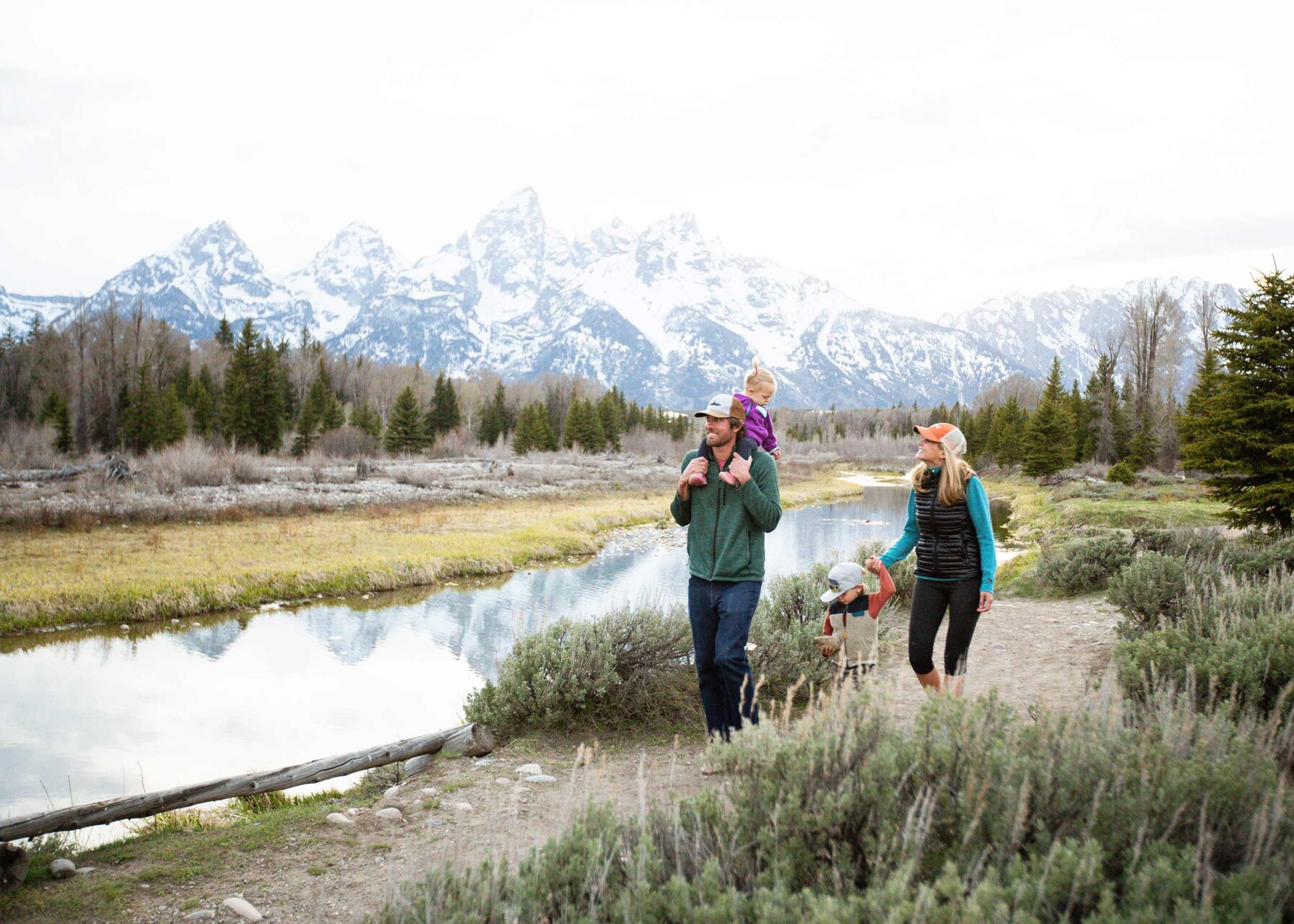 Couple walking with kids along mountain stream with white capped mountains