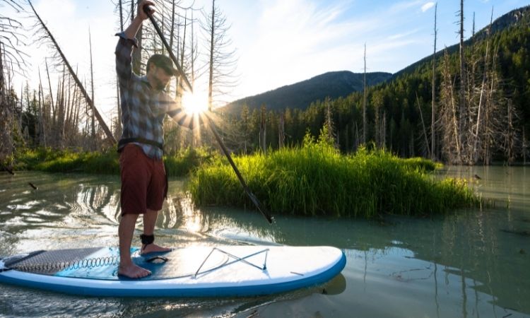 Man paddle boarding on mountain lake.
