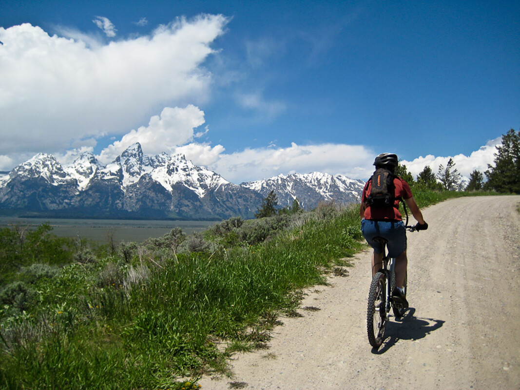 Mountain Biking Jackson Hole biking on mountain road with view of snow capped mountains