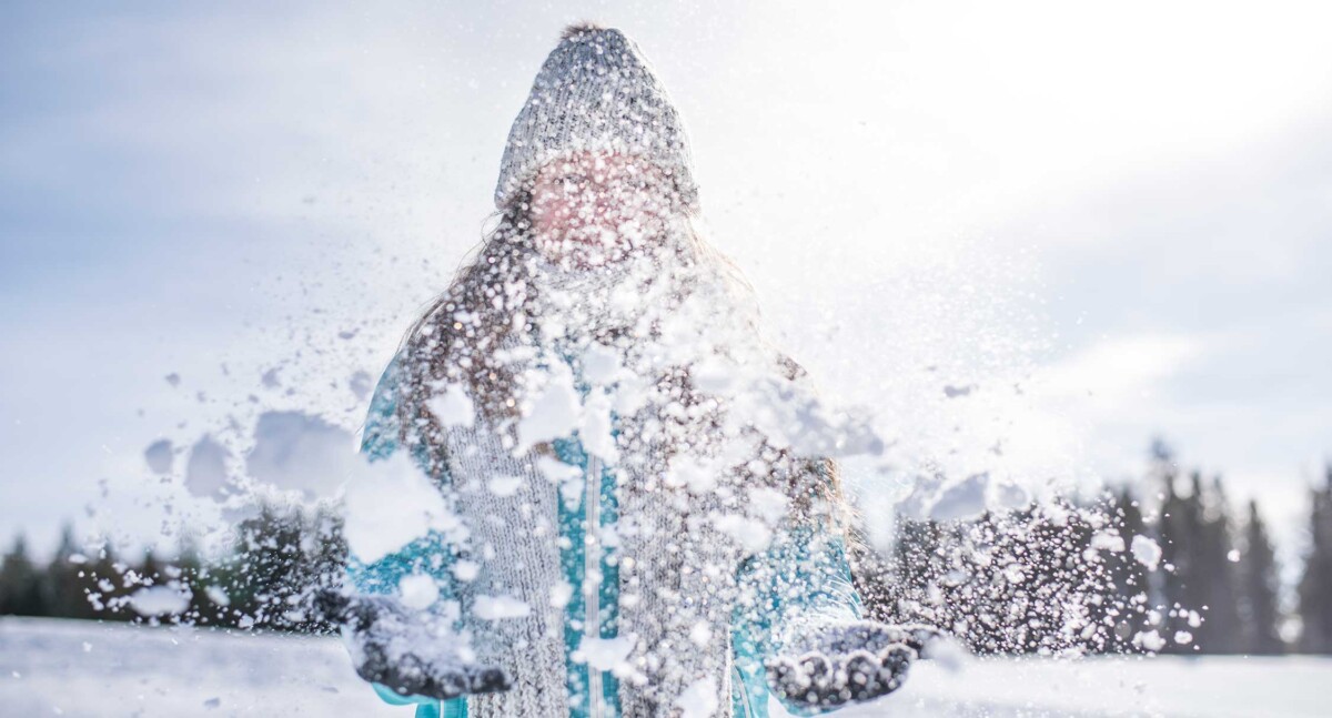 Fun in the Snow woman with winter hat on throwing snow up in the air